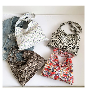 Flat lay of multiple floral and leopard print canvas tote bags with tied strap details
