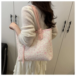 Pink and white woven tote bag shown on a model's shoulder for size and style detail
