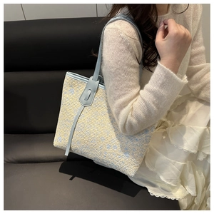 Detailed view of woven pattern and blue leather straps on this large tote bag