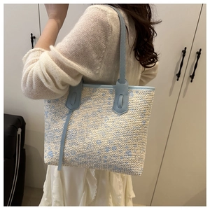 Detail of woven tote bag with light blue floral patterns and leather shoulder straps