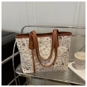 Detailed shot of straw woven tote with heart and smile prints on a shelf background
