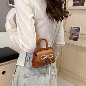 Mini sac à main marron en cuir avec nœud en strass et chaîne en métal en vue lifestyle