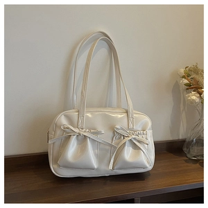 Detail view of cream patent leather tote with functional drawstring pockets and bows