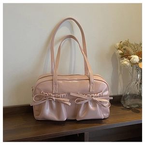 Detail of pink patent leather tote bag with stylish pleated pockets and ribbon bows