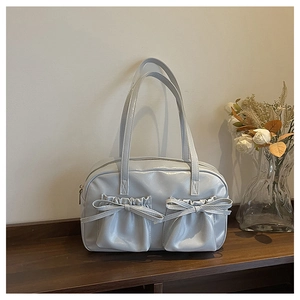 Detailed view of light blue patent leather tote bag with stylish bows and twin front pockets
