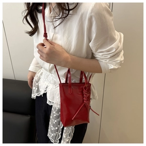 Macro d'un petit sac cabas rouge avec bandoulière à nœud et texte de mode embossé