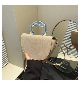 Detail of half-moon woven handbag featuring a unique metallic liquid-effect top handle