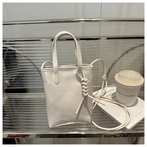 Detail of minimalist cream tote bag with knots and FASHION BAGS text on silver background