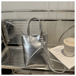 Detailed view of a silver metallic tote bag with decorative rope knots and brand lettering