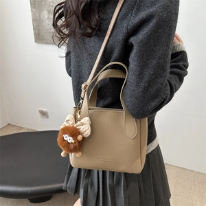 Khaki pebbled leather bucket bag with top handle and brown plush charm accessory