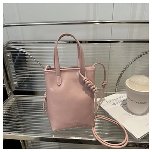 Detail of pink mini tote bag with handles and crossbody strap on metallic background