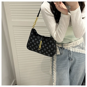 Detailed close-up of retro monogram pattern and gold metal buckle on a black hobo bag