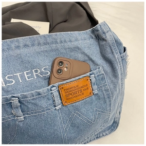 Dettaglio della borsa a tracolla in denim azzurro con ricamo e etichetta in cuoio