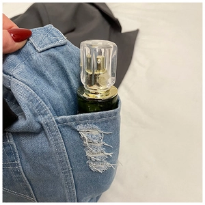 Dettaglio della borsa a tracolla in denim azzurro con bordo della tasca strappato