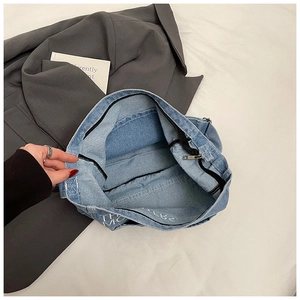 Dettaglio dell'interno della borsa tote in denim blu con tasca a zip e fodera