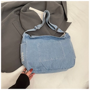 Dettaglio della borsa tote in denim azzurro con bordi sfrangiati e tracolla larga regolabile