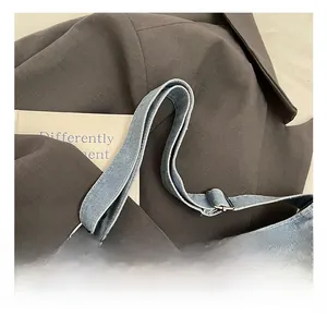 Detail of adjustable washed denim shoulder strap with metal slide buckle on blue bag