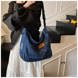 Dettaglio della borsa tote in denim vintage con bordi consumati e toppa in pelle