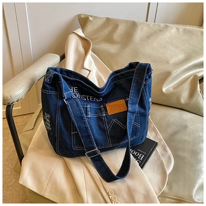 Dettaglio della borsa tote in denim blu scuro con etichetta in pelle su sedia di pelle