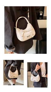 Detail of a creamy white bow handbag featuring pebble grain texture and metal logo