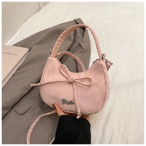 Detail of pink patent leather handbag with bow tie decoration and silver metal logo