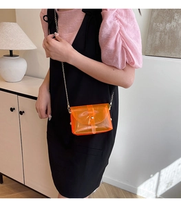 Detail van transparante oranje PVC mini crossbody tas met gouden ketting en gesp