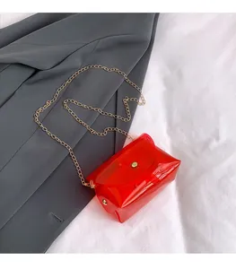 Detailopname van rode transparante enveloptas met gouden metalen ketting en knoop