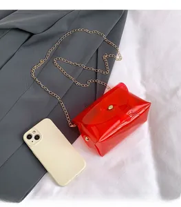 Detail van de rode jelly PVC mini tas vergeleken met een smartphone en gouden ketting