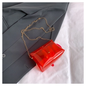 Détail du sac enveloppe transparent rouge avec une élégante chaîne en métal doré