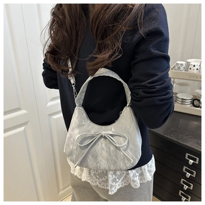 Détail du sac croissant argenté avec texture plissée et grand nœud porté à l'épaule