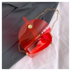 Détail d'un sac enveloppe en PVC rouge translucide avec chaîne dorée et boucle ronde