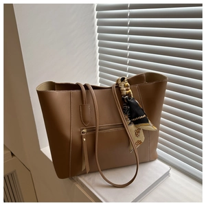 Close-up of brown leather tote bag with elegant silk scarf and functional front zipper pocket
