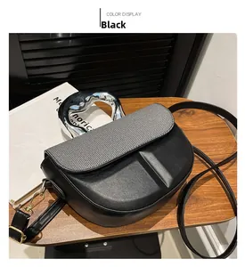 Detail of black saddle bag with striped fabric flap and sculptural silver metal handle