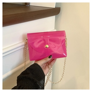 Détail d'un sac gelée rose translucide avec chaîne dorée et bouton métallique de fermeture