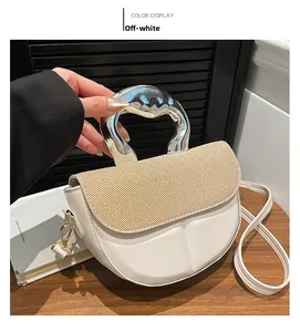 Detail view of off-white crossbody bag with textured flap and silver metallic handle