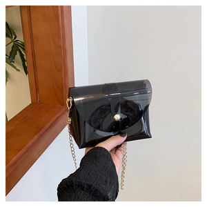 Close-up of black transparent PVC jelly bag with gold chain strap and magnetic snap