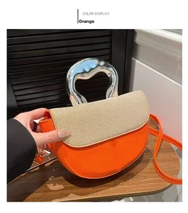 Detail of orange saddle bag featuring cream woven flap and silver irregular metal handle