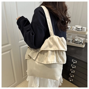 Detail of cream canvas tote bag featuring double ruffle trim and wide shoulder strap