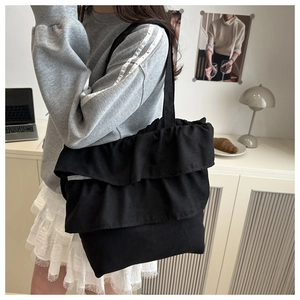 Détail du sac cabas en toile noire avec un design élégant de volants plissés à trois couches