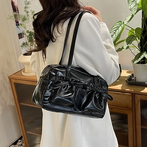 Glossy black patent leather tote bag with bow detail worn on white blazer outfit