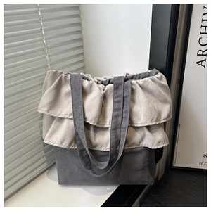 Detail shot of the ruffled lace trim on a charcoal grey canvas tote bag with soft lighting