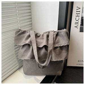 Detail view of the layered ruffle accents on the light gray canvas tote bag surface