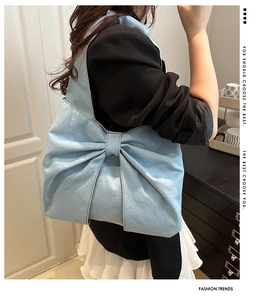 Model wearing a light blue denim tote bag with a large bow detail for daily commute