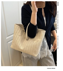 Détail de la texture tressée d'un grand sac cabas en paille beige porté pour l'été