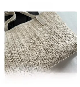 Gros plan détaillé sur la texture en paille tressée et les garnitures en cuir blanc du sac