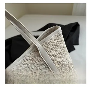 Détail du cabas en paille à motif chevrons avec renforts en cuir de couleur crème