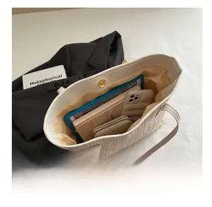 Détail de l'intérieur du grand sac cabas en paille avec tablette, téléphone et portefeuille