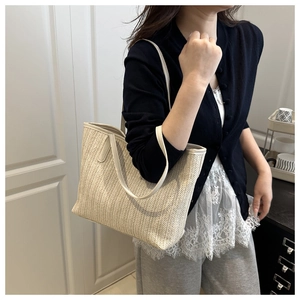 Detailed close-up of a cream woven straw tote bag with long leather straps for women