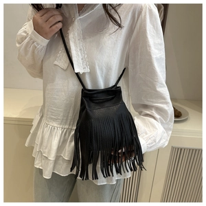 Detail of black pebbled PU leather crossbody bag with long fringes and drawstring closure
