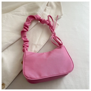 Gros plan sur un sac baguette rose plissé avec texture soyeuse et nœuds latéraux